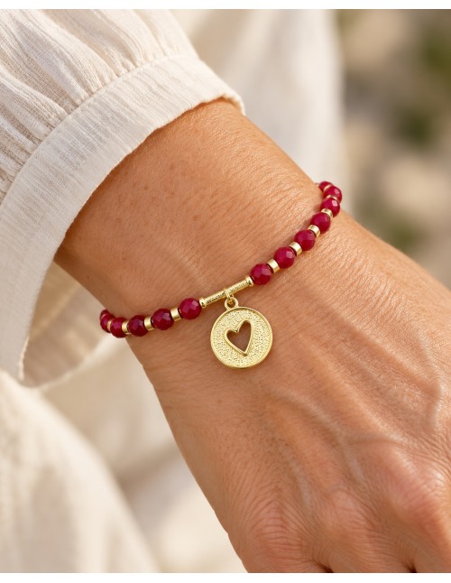 Pulsera roja con medalla de corazón calado bañada en oro sobre fondo blanco 2
